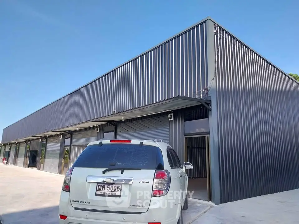 Modern industrial building with sleek metal facade and spacious parking area.