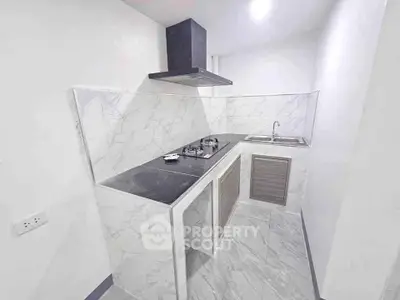 Modern kitchen with sleek marble countertops and gas stove in a compact layout.