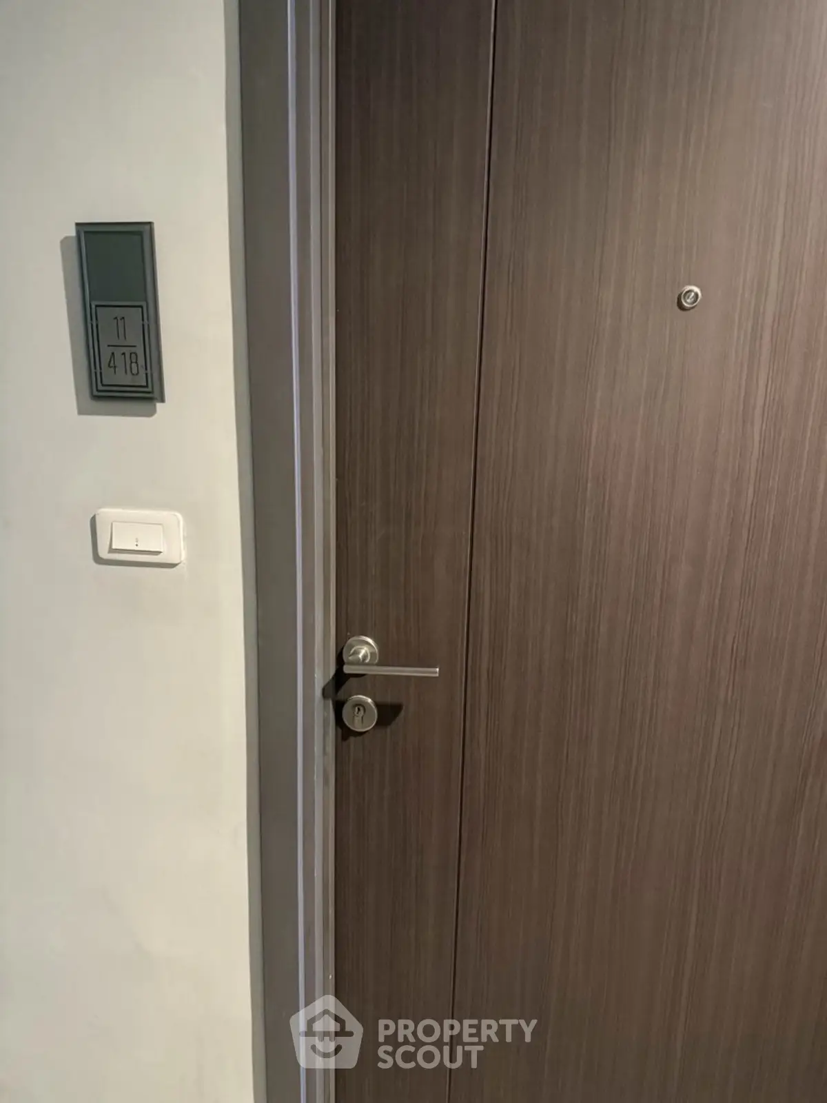 Modern apartment entrance with sleek wooden door and digital room number display.