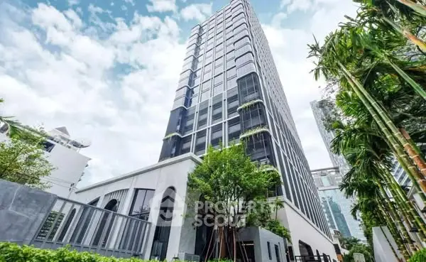 Modern high-rise building with lush greenery and clear sky view.