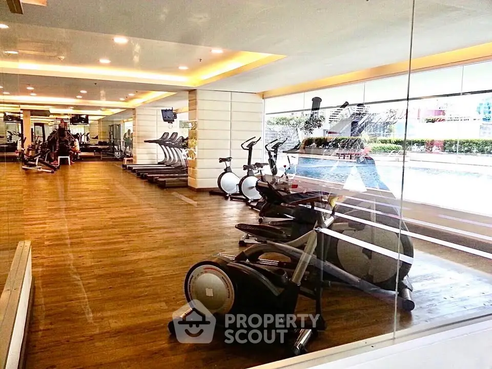 Luxurious gym with modern equipment and pool view in upscale residential complex.
