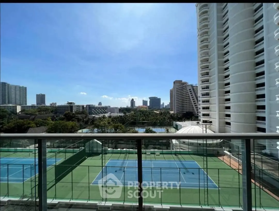 Stunning city view from high-rise balcony overlooking tennis courts and skyline.