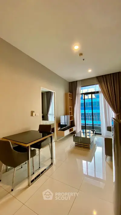 Modern living room with sleek furniture and large window offering city view.