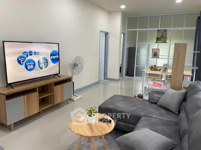 Modern living room with sleek furniture and open layout, featuring a large TV and stylish decor.