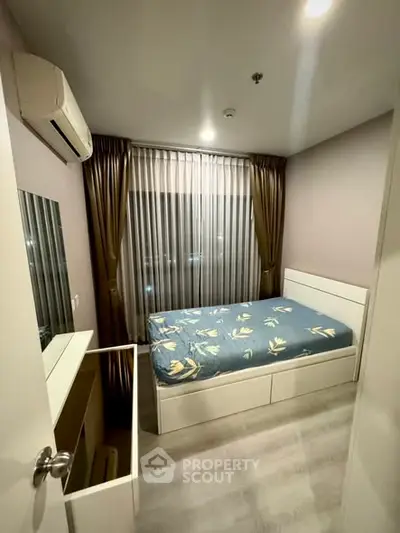 Cozy bedroom with modern furnishings and large window for natural light.