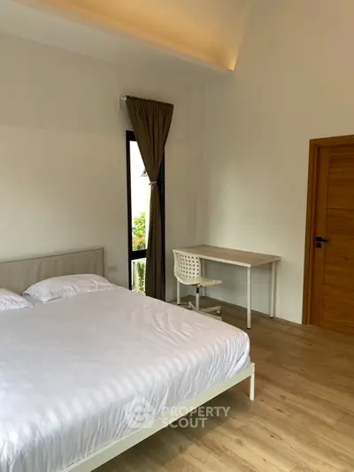 Spacious bedroom with modern decor and natural light, featuring a comfortable bed and a study desk.
