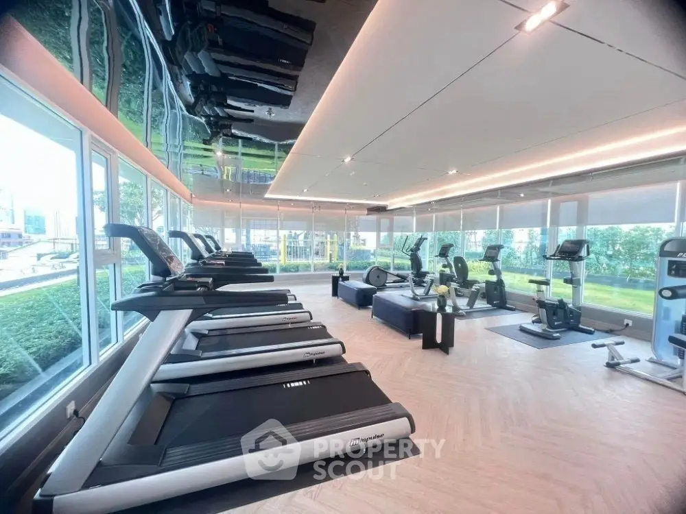 Modern gym with state-of-the-art equipment and panoramic windows in luxury real estate property.