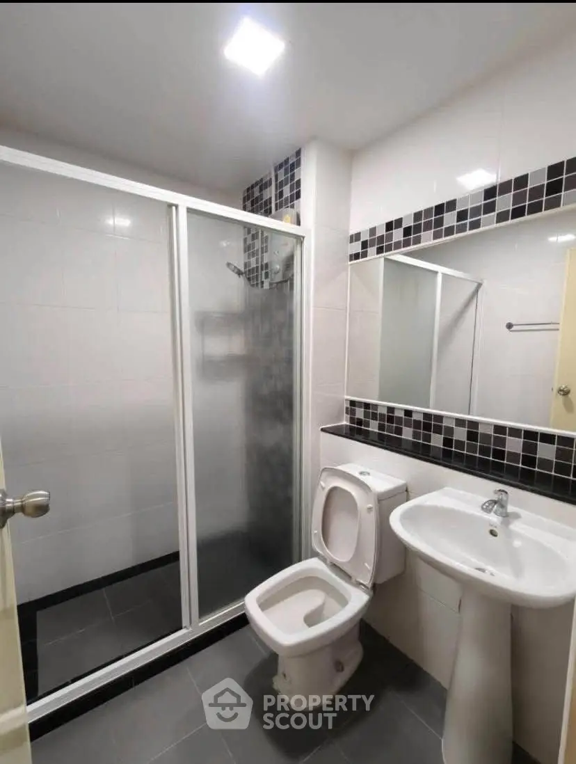 Modern bathroom with sleek shower and stylish black and white tiles.
