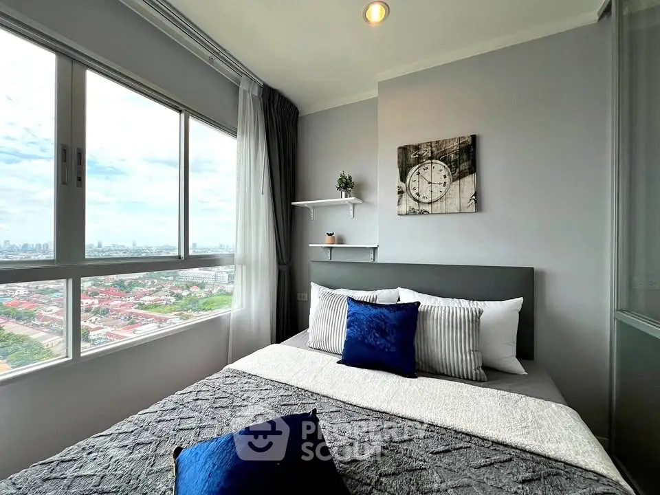 Modern bedroom with large window offering stunning city views, featuring stylish decor and cozy bedding.
