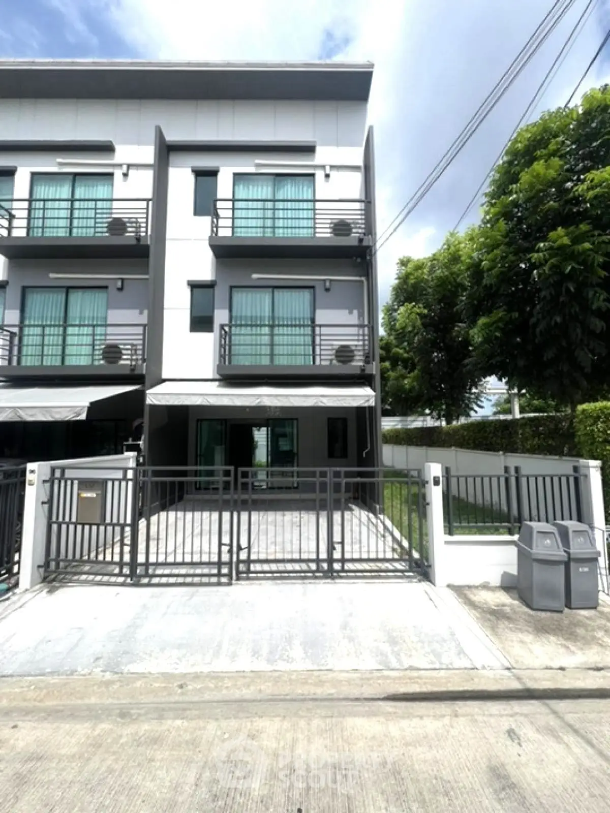 Modern three-story townhouse with gated entrance and balcony, perfect for urban living.
