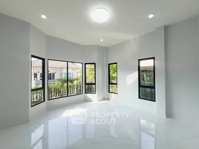 Spacious sunlit room with large windows and modern design, perfect for a bright living space.