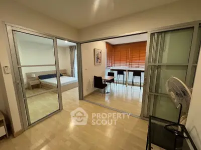 Spacious modern apartment with sliding glass doors and wooden flooring, featuring a cozy bedroom and dining area.