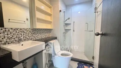Modern bathroom with glass shower and sleek fixtures in contemporary apartment.