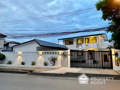 Modern two-story house with gated entrance and sleek exterior design.