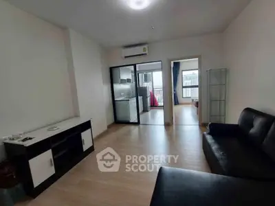 Spacious modern living room with sleek furniture and open layout, leading to a bright balcony view.
