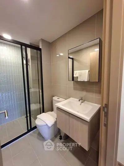 Modern bathroom with sleek fixtures and glass shower enclosure in a contemporary apartment.