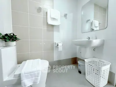Modern bathroom with sleek fixtures and neutral tiles, featuring a large mirror and white accents.