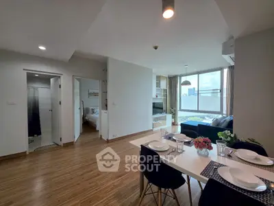 Modern open-plan living room with dining area and city view, featuring sleek furniture and abundant natural light.
