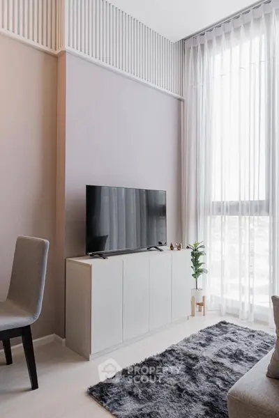 Modern living room with sleek TV stand, plush rug, and floor-to-ceiling windows for natural light.