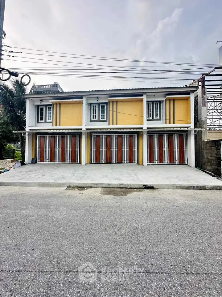 Modern two-story building with multiple garage doors and vibrant yellow facade.