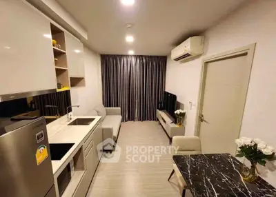 Modern compact living room with open kitchen, stylish decor, and cozy ambiance in a contemporary apartment.