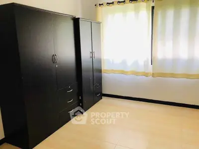 Spacious bedroom with ample natural light and sleek black wardrobes.