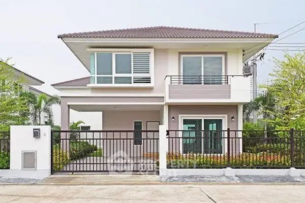 Modern two-story house with gated entrance and lush greenery