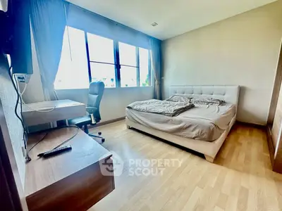 Spacious bedroom with large window and modern furnishings