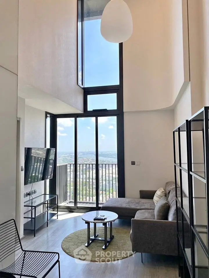 Modern living room with high ceilings and large windows offering stunning city views.