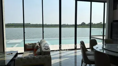 Luxurious living room with stunning lake view and infinity pool, featuring elegant furniture and floor-to-ceiling windows.