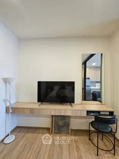 Modern living room with sleek TV stand, stylish chair, and elegant floor lamp on wooden flooring.