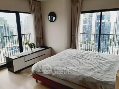 Spacious bedroom with stunning city view and large windows in modern apartment.