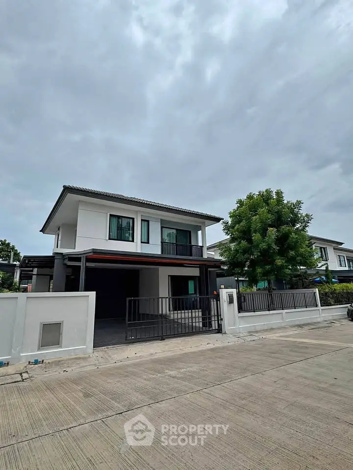Modern two-story house with sleek design and spacious driveway in a suburban neighborhood.