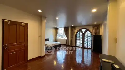 Spacious bedroom with elegant arched windows and polished wooden floors