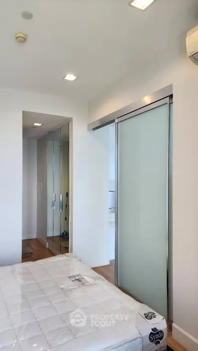 Modern bedroom with sliding glass door and mirrored closet in a bright apartment.