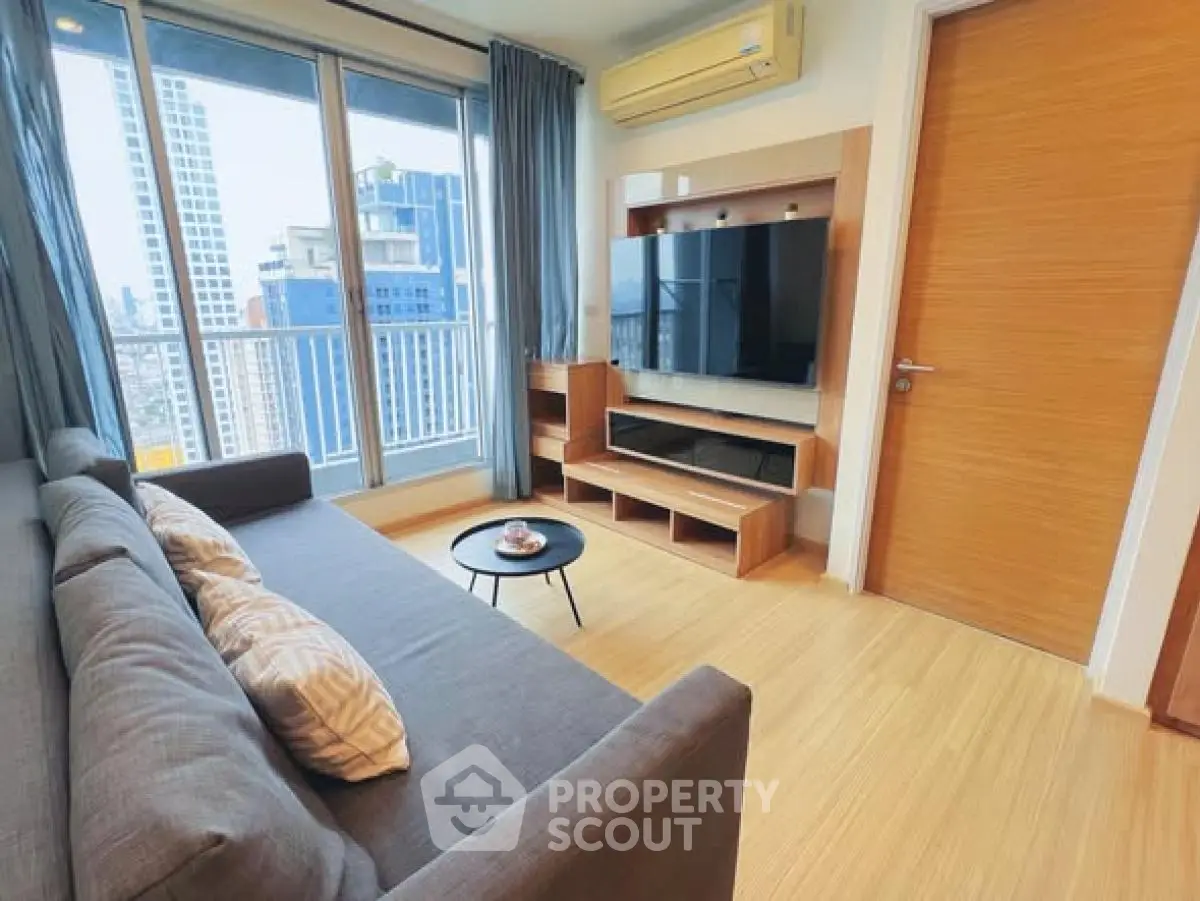 Modern living room with city view, featuring sleek furniture and large windows.