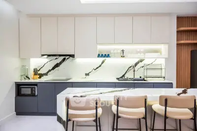 Modern kitchen with sleek design, marble countertops, and stylish bar seating.