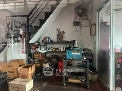Spacious storage area with shelves and tools under staircase, ideal for workshop or garage use.