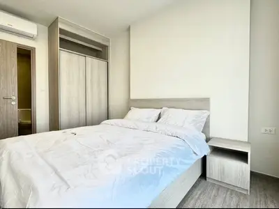 Modern bedroom with minimalist design and ample natural light, featuring a comfortable bed and built-in wardrobe.
