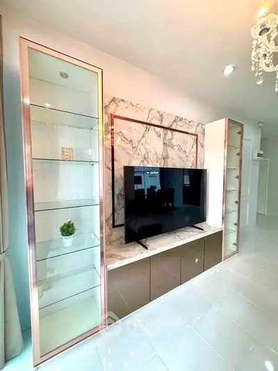 Modern living room with sleek TV unit and marble accents, showcasing elegant glass shelving and stylish decor.