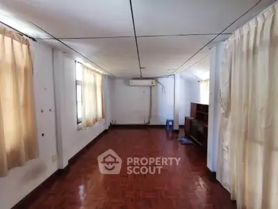 Spacious empty room with wooden flooring and large windows