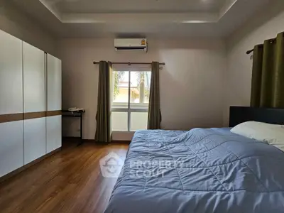 Spacious bedroom with modern decor and large window offering natural light.