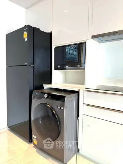 Modern kitchen with sleek appliances including fridge and washing machine, perfect for urban living.