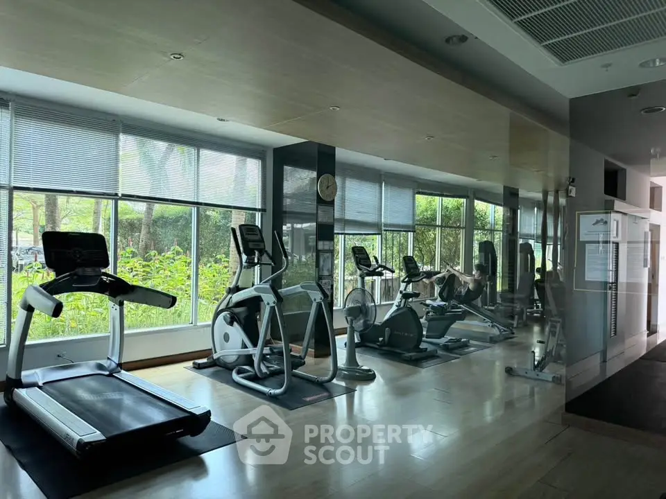 Modern gym with large windows and exercise equipment in a residential building.