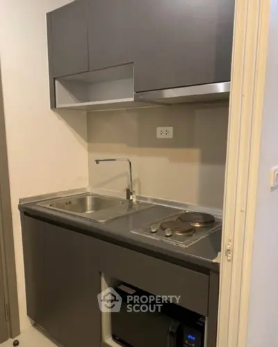 Compact modern kitchen with sleek cabinetry and electric stove in a cozy apartment.