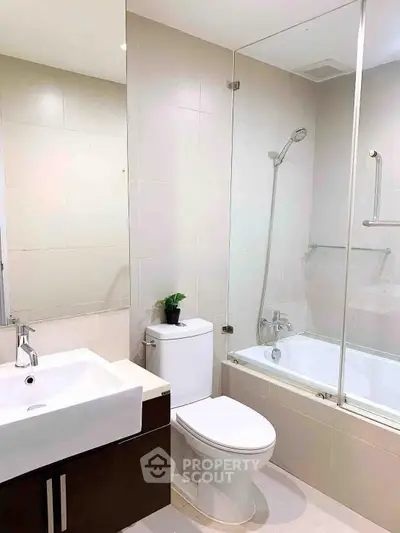 Modern bathroom with sleek fixtures and glass-enclosed bathtub in a contemporary apartment.