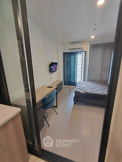 Modern bedroom with sleek design, featuring a wall-mounted TV, desk, and large window for natural light.