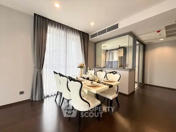 Elegant dining area with stylish chairs and large windows in modern apartment.