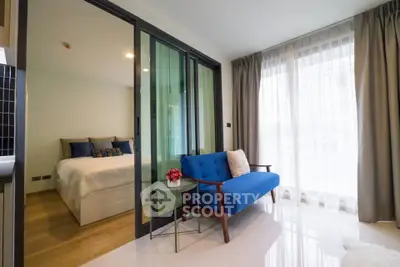 Modern apartment with glass partition, cozy blue sofa, and bright natural light.