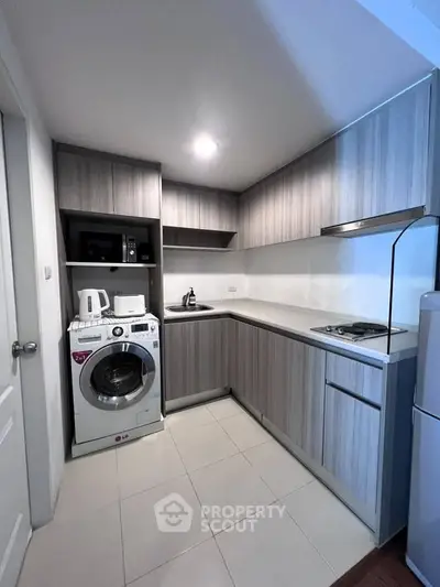 Modern kitchen with sleek cabinetry, washing machine, and built-in appliances in a compact layout.